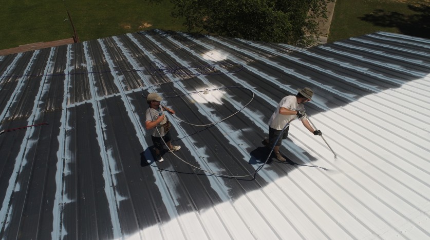 Deux ouvriers peignent une toiture en blanc